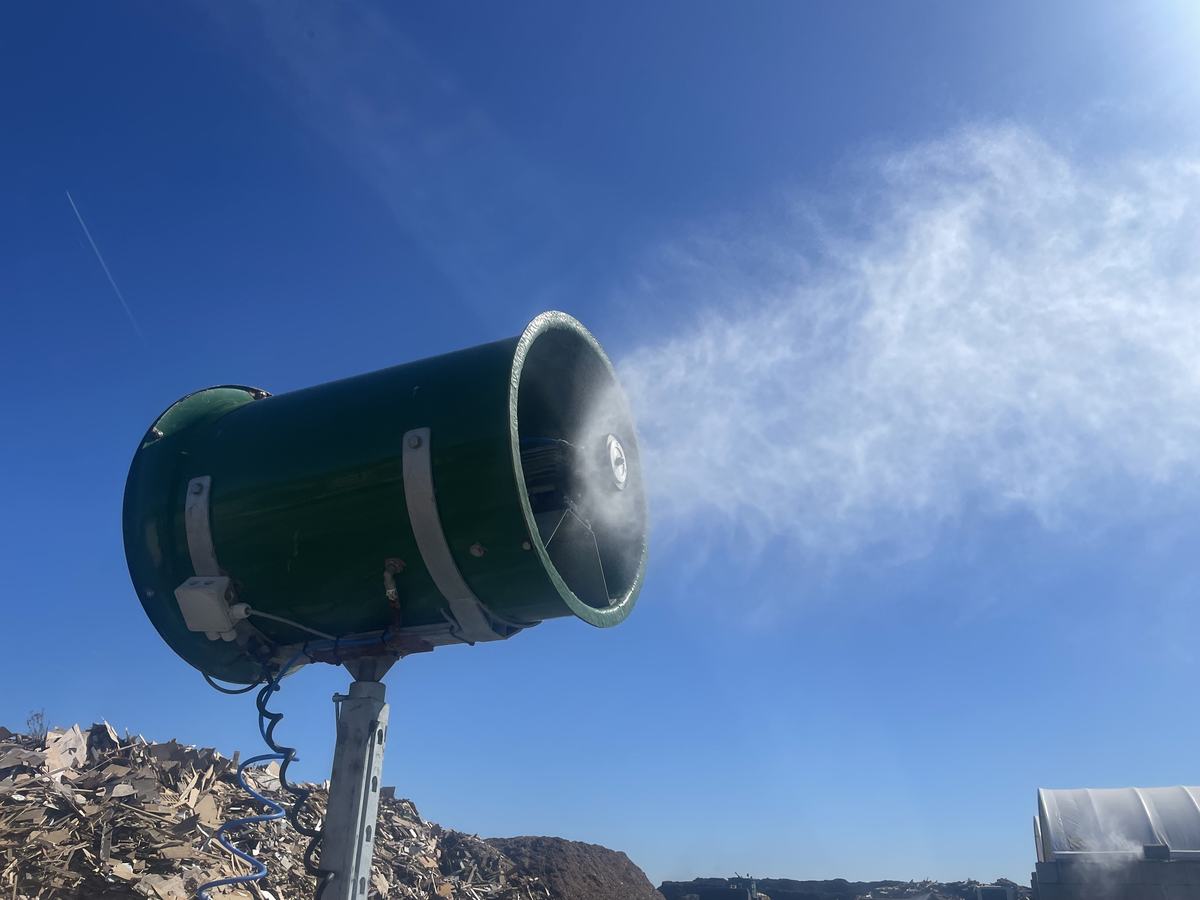 Mast-mounted atomiser unit projecting neutralising mist against a clear sky