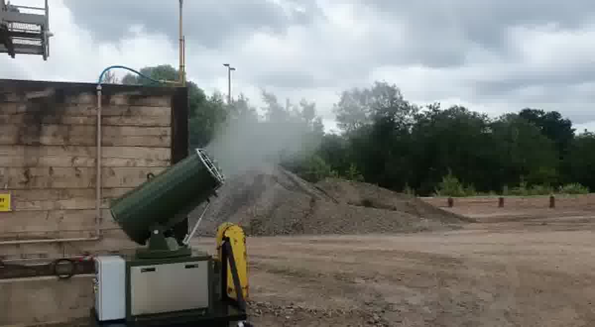 Mobile dust cannon projecting mist across a site